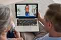 Over shoulder view of old couple patient video calling virtual doctor on laptop.