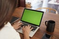 Over shoulder view of woman sitting at table using laptop computer at home, close up