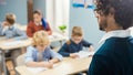 Over the Soulder Shot of Teacher Explaining Lesson to Classroom Full of Diverse Bright Children, I