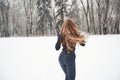 Over there, where our car is. Rear view of girl with long hair runs near the forest to the automobile in wintertime Royalty Free Stock Photo