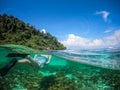 Over and Underwater Dome Shot of man snorkling in front of a private sailing yacht in Thailand over a coral reef Royalty Free Stock Photo