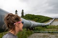 Young adult female tourist admires the Trans Alaskan Pipeline