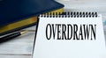 OVERDRAWN - word in a notebook on the background of a weekly and a pen Royalty Free Stock Photo