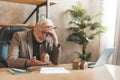 Overdue mortgage payment. Senior man holding a model house in his hands in despair. Pledged housing, problems with the house Royalty Free Stock Photo