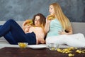 Overeaten women lying at coach eating fast food Royalty Free Stock Photo