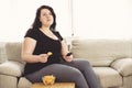 Overweight woman with tv remote and junk food Royalty Free Stock Photo