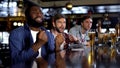 Overemotional afro-american man cheering for favorite team with friends in bar