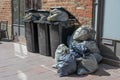 Overfilled trash bins and rubbish bags full of garbage on the pavement in the city, daily waste output from the affluent society Royalty Free Stock Photo