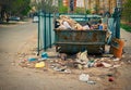 Overfilled trash dumpster in ghetto neigborhood. A lot of litter about