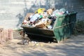 Overfilled trash dumpster in ghetto neigborhood in