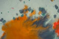Overflowing bright orange and dark blue paint on paper