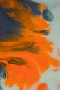 Overflowing bright orange and dark blue paint on paper