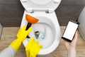 Overflowing broken toilet. clogged toilet. a smartphone with a white screen for advertising about plumbing. girl looking Royalty Free Stock Photo