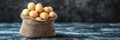 Overflowing Burlap Sack Full of Shelled Macadamia Nuts Set Against a Dark, Textured Background Royalty Free Stock Photo
