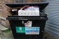 Overflowing commercial waste bin rear of shops