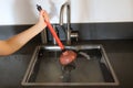 Overflowing kitchen sink, clogged drain. Hand holding plunger. Royalty Free Stock Photo