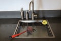 Overflowing kitchen sink, clogged drain. Plunger force cup and yellow rubber duck in the sink.