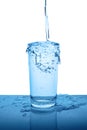 Overflowing mineral water in transparent glass with drops and bu Royalty Free Stock Photo