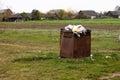 Overflowing rusty trash can in the countryside. Rubbish scattered on the ground, environmental protection problem