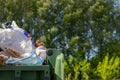 An overflowing trash can on a forest background. Human concept harming the ecology of the planet need for sorting and recycling