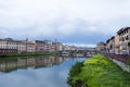 Overgrown Arno river bank with Ponte Santa Trinita StTrinity bridge and Florence cityscape in Italy Royalty Free Stock Photo