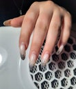 Overgrown gel polish on the hand on the background of a vacuum cleaner. Removing the long nail coating in the salon. Royalty Free Stock Photo