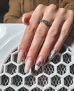 Overgrown gel polish on the hand on the background of a vacuum cleaner. Removing the long nail coating in the salon. Royalty Free Stock Photo