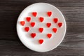 Overhead above top close up view photo of yummy tasty cute gummy red small little tiny hearts in on round white plate on kitchen s