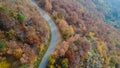 Overhead aerial top view over curve road bend in colorful countryside autumn forest.Fall orange,green,yellow,red tree