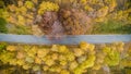 Overhead aerial top view over straight road in colorful countryside autumn forest.Fall orange,green,yellow,red tree