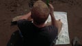 Overhead angle: Jittery man on towel tries to relax at beach with a drink