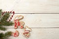 Overhead of Christmas New Year holiday background. Red gingerbread cookies deer, elk, candy cane and fir branch tree on white woo Royalty Free Stock Photo