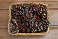 Close up of group of pine cones, with dried red berries. in wicker basket on wood table