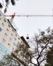 Overhead crane for building construction work going on in the city buildings and trees