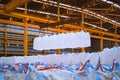 Overhead crane lift jumbo bags of tapioca using spread bar in storage warehouse. Bulk cargo in jumbo bag handling equipmet.