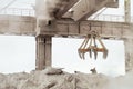 Overhead crane with mechanical multivalve clamshell grab in hot outdoors industrial plant shop