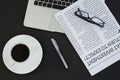 Cup of coffee, laptop, spectacles, newspaper and pen on black background Royalty Free Stock Photo