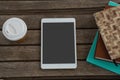 Disposable glass, books and digital tablet on wooden plank Royalty Free Stock Photo