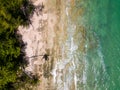 Overhead drone view of a small tropical beach surrounded by palm trees and shallow ocean