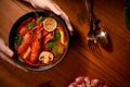 Overhead, A female chef serving a Thai spicy soup with shrimps. Tom Yam Kung bowl