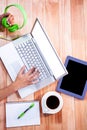 Overhead of feminine hands typing on laptop and holding headphones