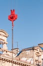 Overhead, Industial, crane hoist and hook, and 1500\'s building, against a blue sky