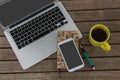 Laptop, mobile phone, dairy, pen and coffee on wooden plank Royalty Free Stock Photo