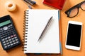 Overhead of office table with notebook, pen, mobile phone , calculator, eye glasses and ffice supplies, gadgets in modern office Royalty Free Stock Photo