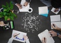 Overhead of people writing with white jigsaw doodle against grey background