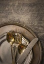 Overhead perspective of tarnished silver plated flat ware and platter with worn pewter dish on rustic steel background. Vintage fi