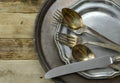 Overhead perspective of tarnished silver plated flat ware and platter with worn pewter dish on rustic wooden table background. Cop