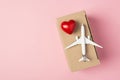 Overhead photo of airplane and box humanitarian aid donation with red heart isolated on the pink background with blank space