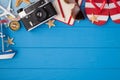 Overhead photo of camera starfish planner pencil sunglasses map airplane compass ship and sandals isolated on the blue wooden Royalty Free Stock Photo