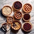 Overhead photo of different pies, tarts, and deserts on white marble table